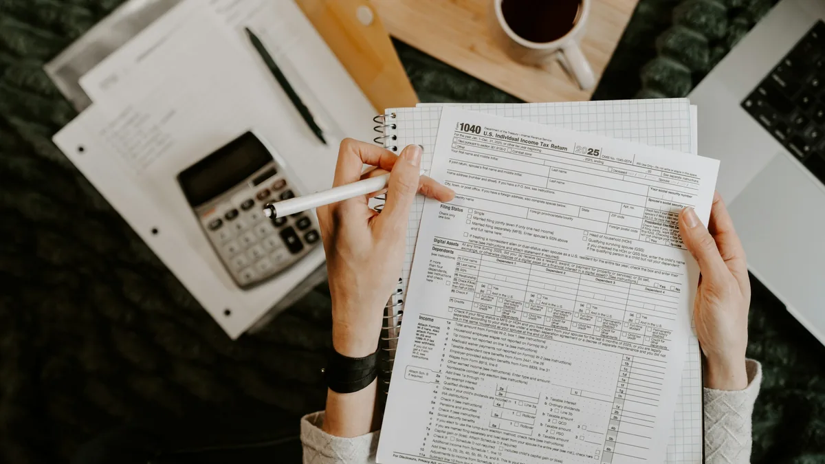 Person reviewing loan paperwork with a calculator and laptop