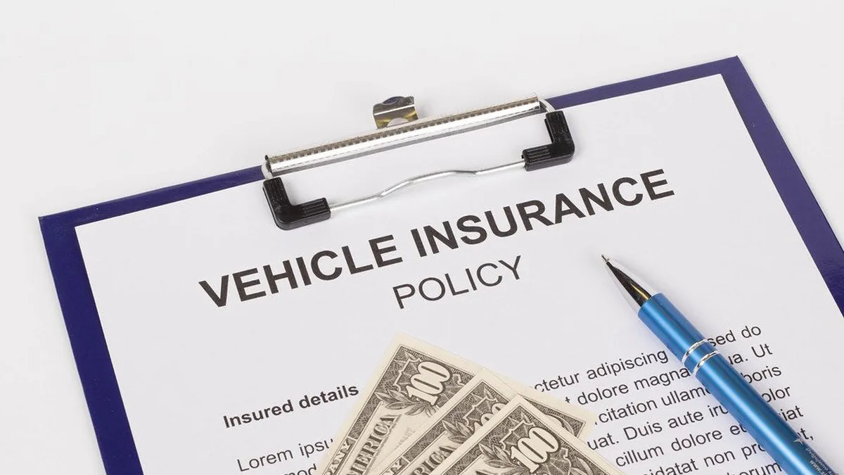 Vehicle insurance policy document on a clipboard with a pen