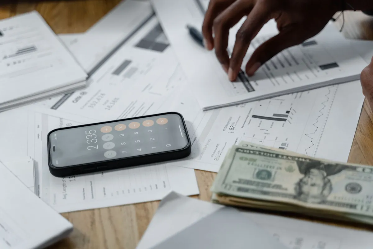 Hands using a calculator while reviewing financial paperwork