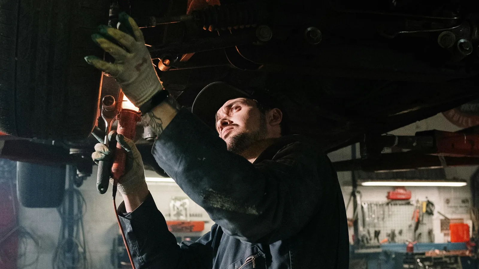 Mechanic working underneath a raised vehicle in an auto repair shop