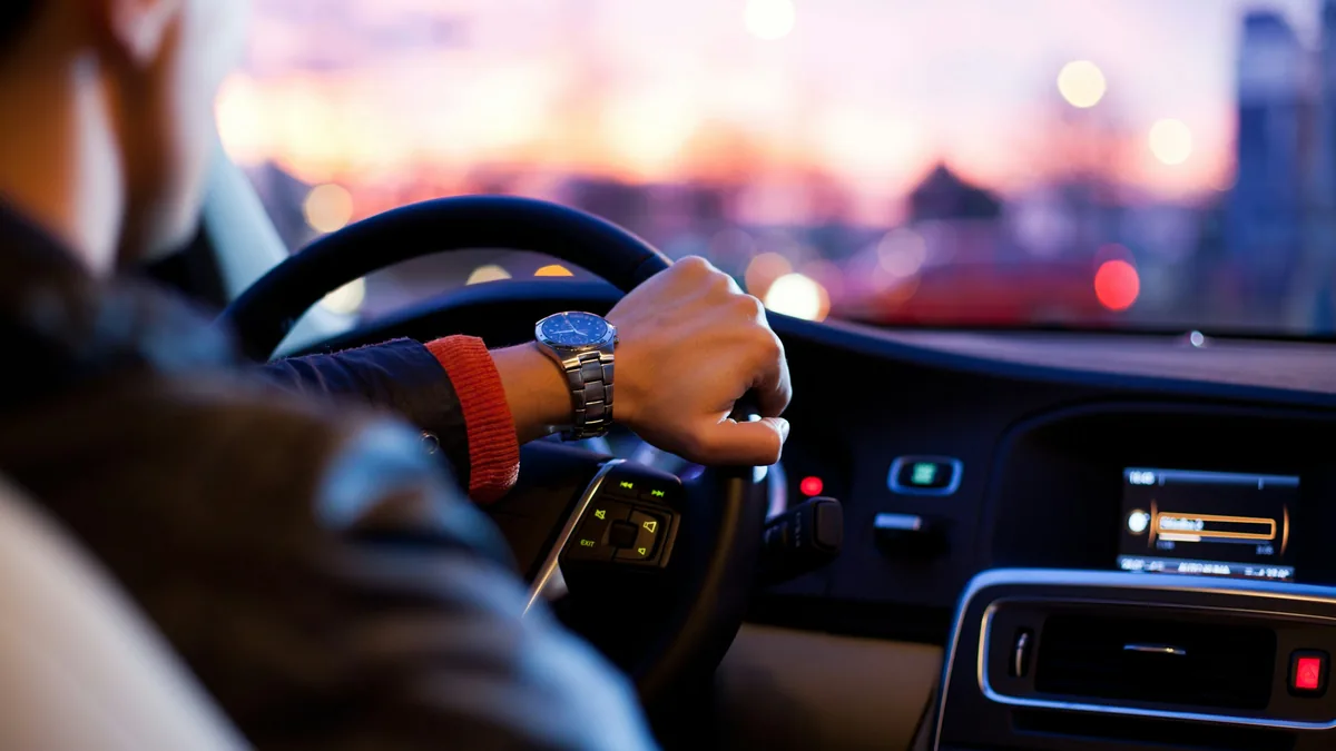 Driver's hands on a steering wheel while driving on a highway